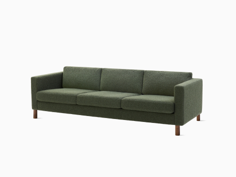 Un divano Lispenard grigio con imbottiture in tessuto e gambe in legno di noce, vista angolare.