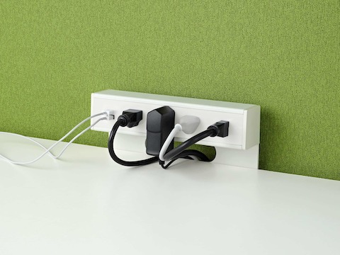 USB-A port and cable, USB-C port and cable , and four A/C power outlets with cables plugged into an attached table power source on green fabric background.