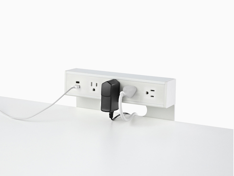 USB-A port and cable, USB-C port, and four A/C power outlets with two cables plugged into an attached table power source. USB-A port and cable, USB-C port, and four A/C power outlets with two cables plugged into an attached table power source.