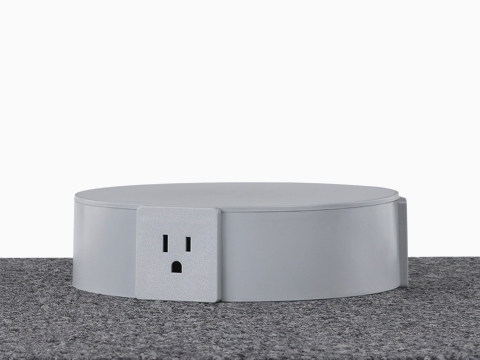 A close-up view of a light gray Logic Reach Electrical Hub sitting on carpet. 