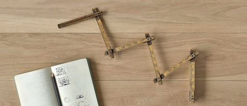 An overhead view of an antique folding ruler with a notebook and pencil on a wood surface.