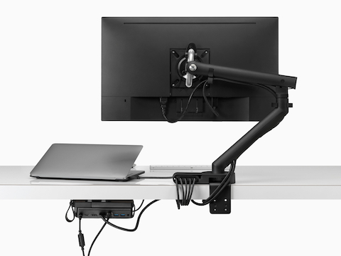 Visão traseira de uma tela de monitor com cabos de alimentação e de dados roteados a partir do braço para monitor conectado e por meio de um módulo de conectividade e Micro Loop Ondo sob uma mesa.