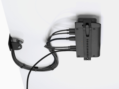 Loop Micro Mount attached under a desk cradling a thin client or power docking station with attached cables that are routed tidily to the edge and above the desk.