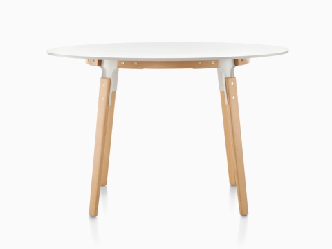 A round Magis Steelwood Table with a white top and wood legs in a light finish. 