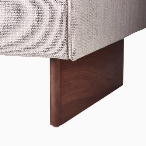 A detailed crop of a Walnut Wood Base on a Mantle Ottoman upholstered in Capri Stone.