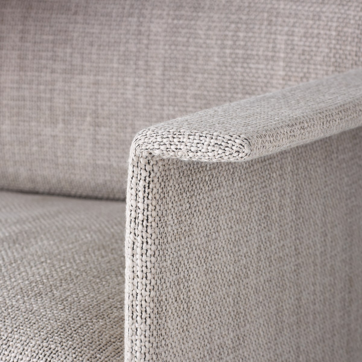 Vista en detalle del brazo de un sofá de tres asientos Mantle tapizado en Capri Stone y ribete de cuero.