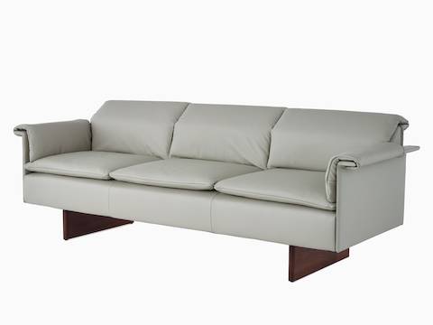 Visão angular de um sofá de três lugares Mantle estofado em Rhythm Khaki com uma base em madeira de carvalho.