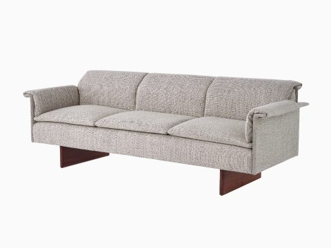 Angled view of a Mantle Three Seater Sofa upholstered in Capri Stone with a Walnut Wood Base. Angled view of a Mantle Three Seater Sofa upholstered in Capri Stone with a Walnut Wood Base.