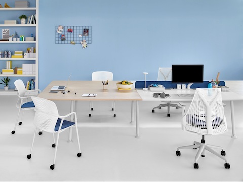 Angrenzende Memo-Kollaborations- und Arbeitsflächen, die von weißen Keyn- und Sayl-Stühlen mit blauen Sitzen bedient werden.