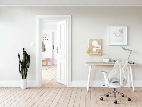 A white Memo Desk and white Sayl Chair in a light and airy home office setting with a partly open door. 