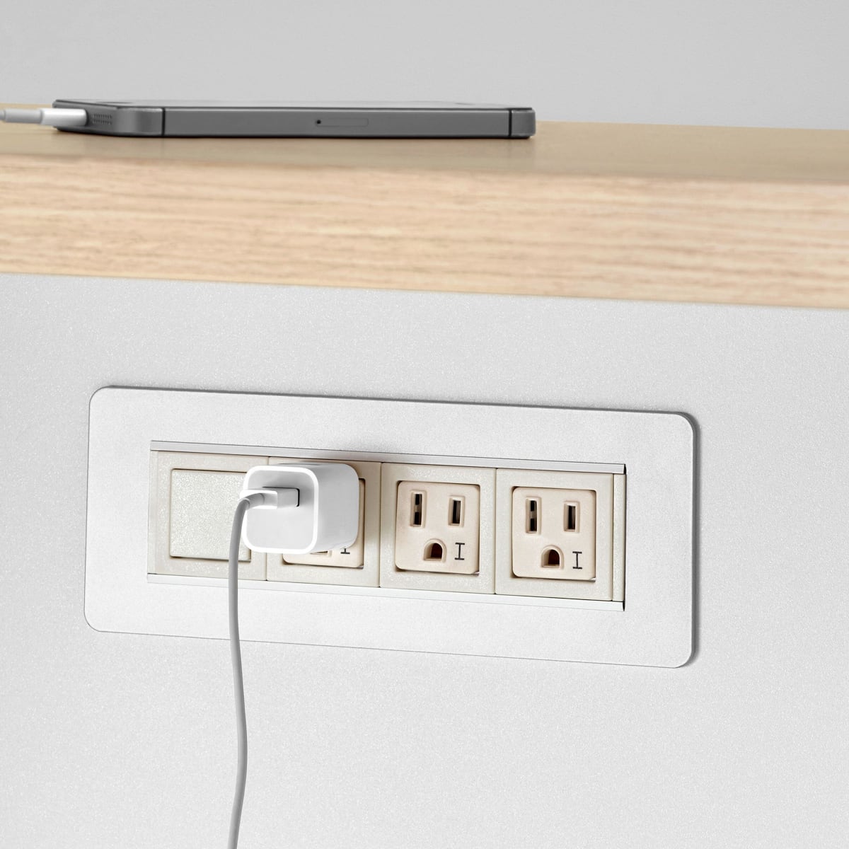 Close up image of a white Meridian Storage power unit with three AC outlets and a white power cable plugged into one of the outlets.