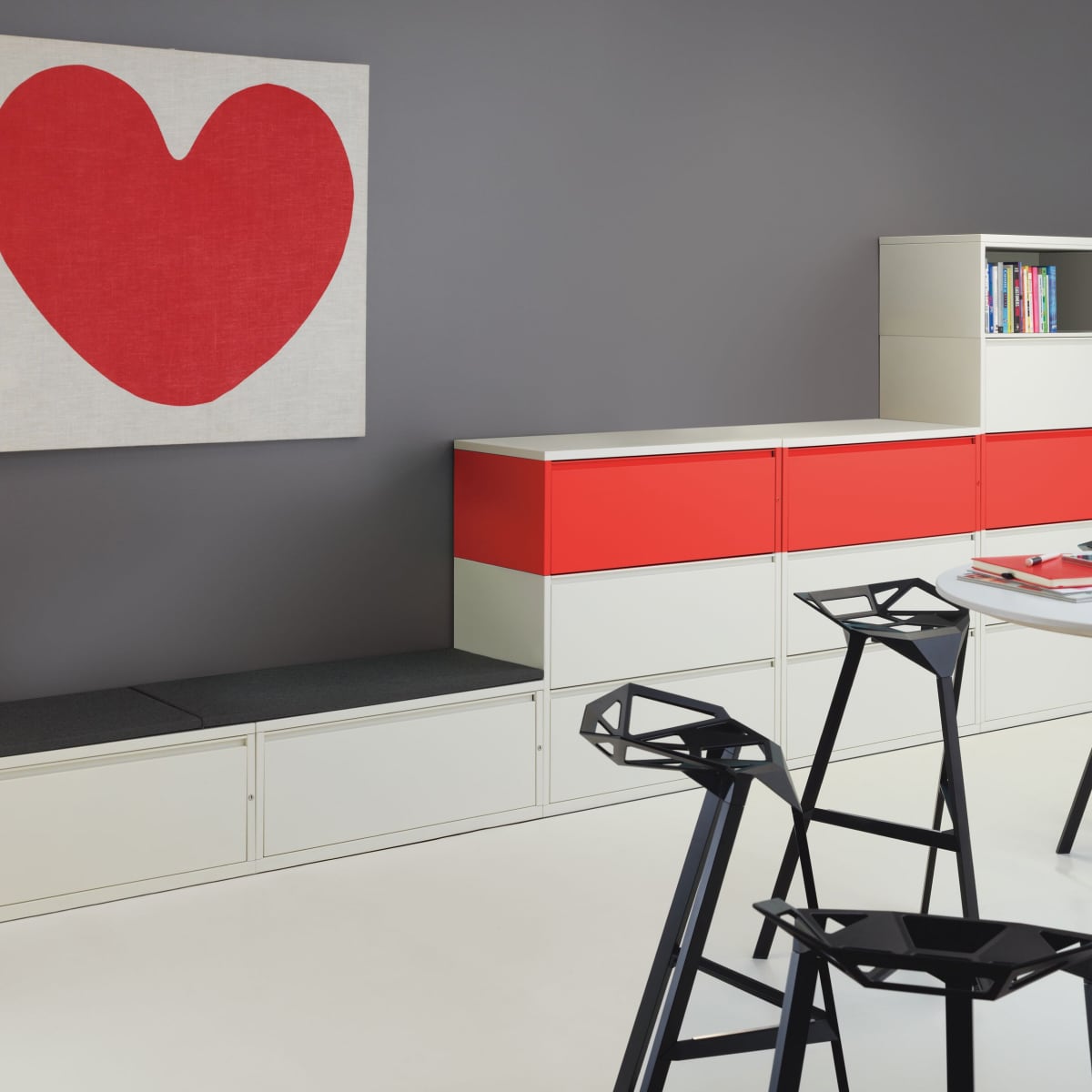 White and red Meridian Storage lateral files stacked on top of each other with black and white laminate tops and collaborative tables with stools in the foreground.