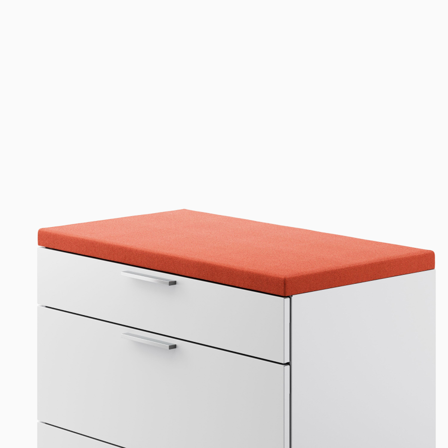 Close up of a light gray Meridian Storage lateral file with a red cushion top. viewed from an angle.