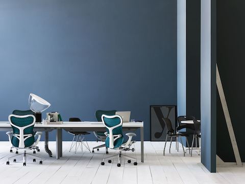 Blue Mirra 2 office chairs and black Caper Stacking Chairs in a video conferencing area featuring a Layout Studio benching system.