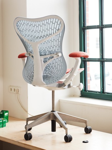 A blue Mirra 2 office chair, viewed from the rear and set close to a window.