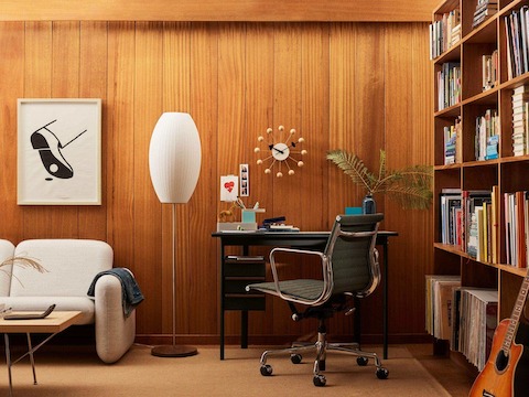 木板结构的图书室里放着一张配沙石色桌面的黑色Mode办公桌，搭配一盏雪茄型台灯和奶油色的Wilkes沙发。