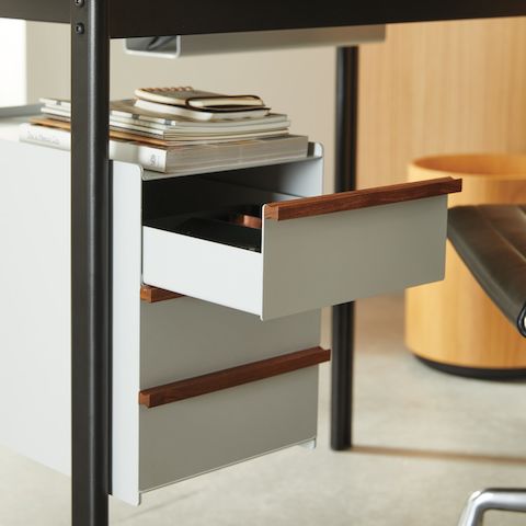 Dettaglio di una scrivania Mode nera con cassetti Sandstone e maniglie in legno in un ufficio domestico.
