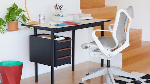 Un ufficio domestico moderno con una scrivania Mode con cassetti Nightfall e piano Sandstone, vicina a una seduta Cosm bianca.