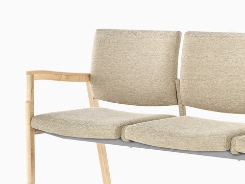 Partial view of beige Monarch Multiple Seating, showing a sculpted wood arm and memory foam seat.