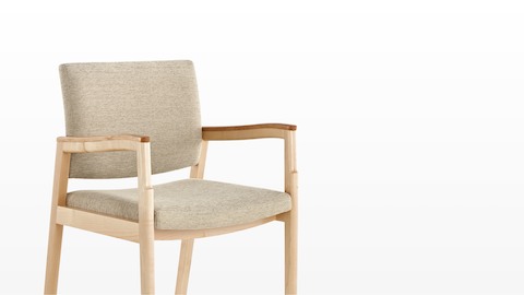 Angled view of a Monarch Multiple Seating chair with beige upholstery and a solid maple frame.