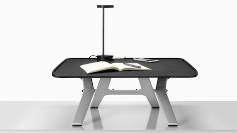 A Monto Sit-Stand Riser in a raised position with a black Lolly Lamp. A Monto Sit-Stand Riser in a raised position with a black Lolly Lamp.