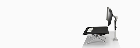 Uma visão lateral de um suporte sit-to-stand Monto em posição elevada e acompanhado de uma grande tela curvada em um braço para monitor Ollin branco.