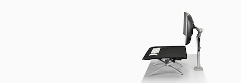 A side view of a Monto Sit-Stand Riser in a raised position and paired with a large curved screen on a white Ollin Monitor Arm. A side view of a Monto Sit-Stand Riser in a raised position and paired with a large curved screen on a white Ollin Monitor Arm.