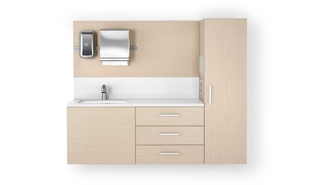 A Mora casework wall in an ash finish consisting of a 3-drawer storage case, a waredrobe, and a wall panel with a soap dispenser and paper towel dispenser. The white solid surface has an integrated sink and backsplash.