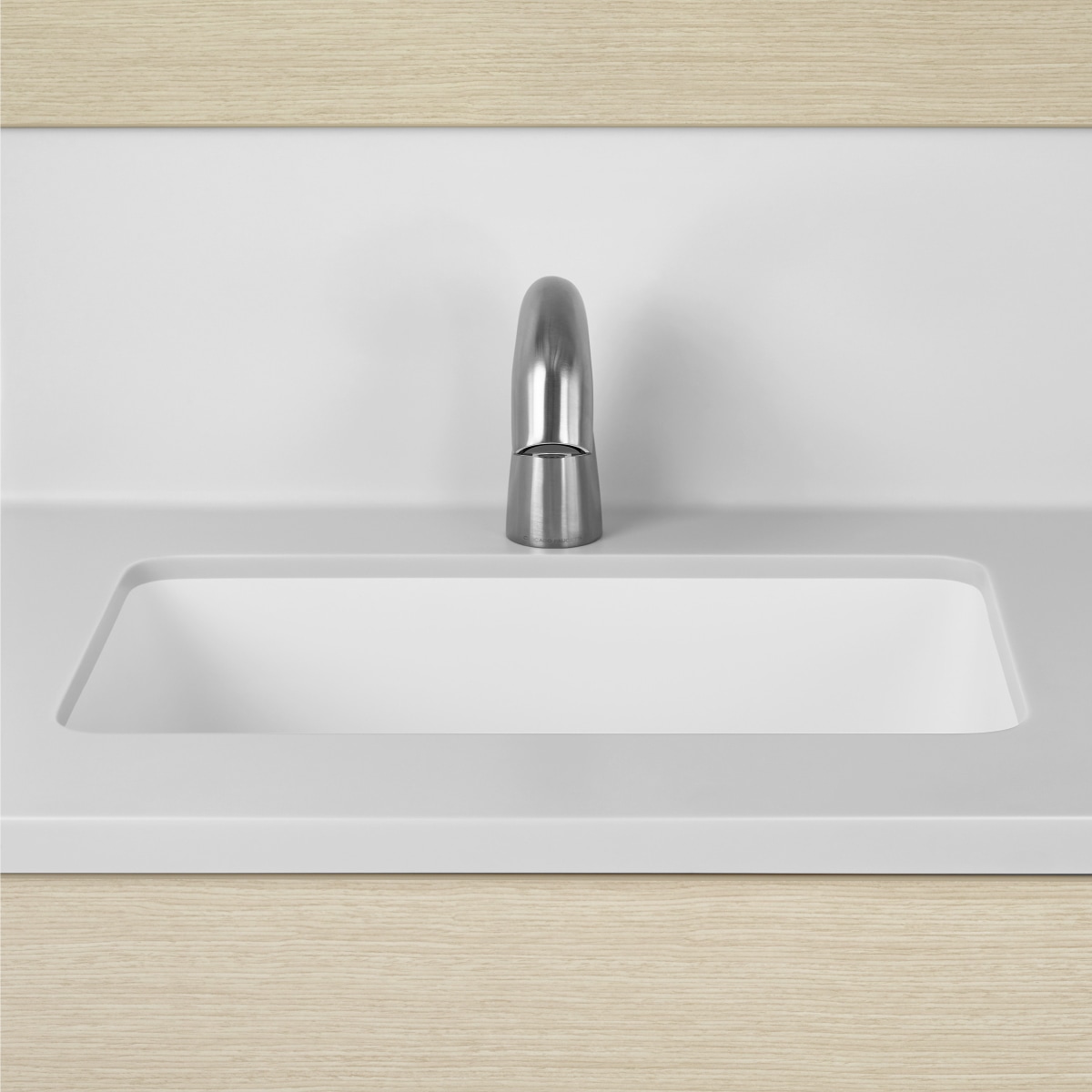 A close-up view of a Mora Casework integrated sink and backsplash in white solid surface.