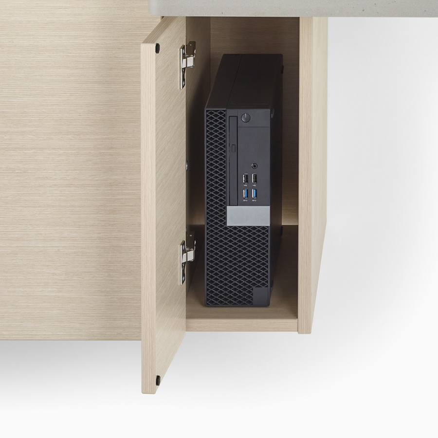A close-up view of a Mora Casework technology storage cabinet in an ash finish holding a black printer.