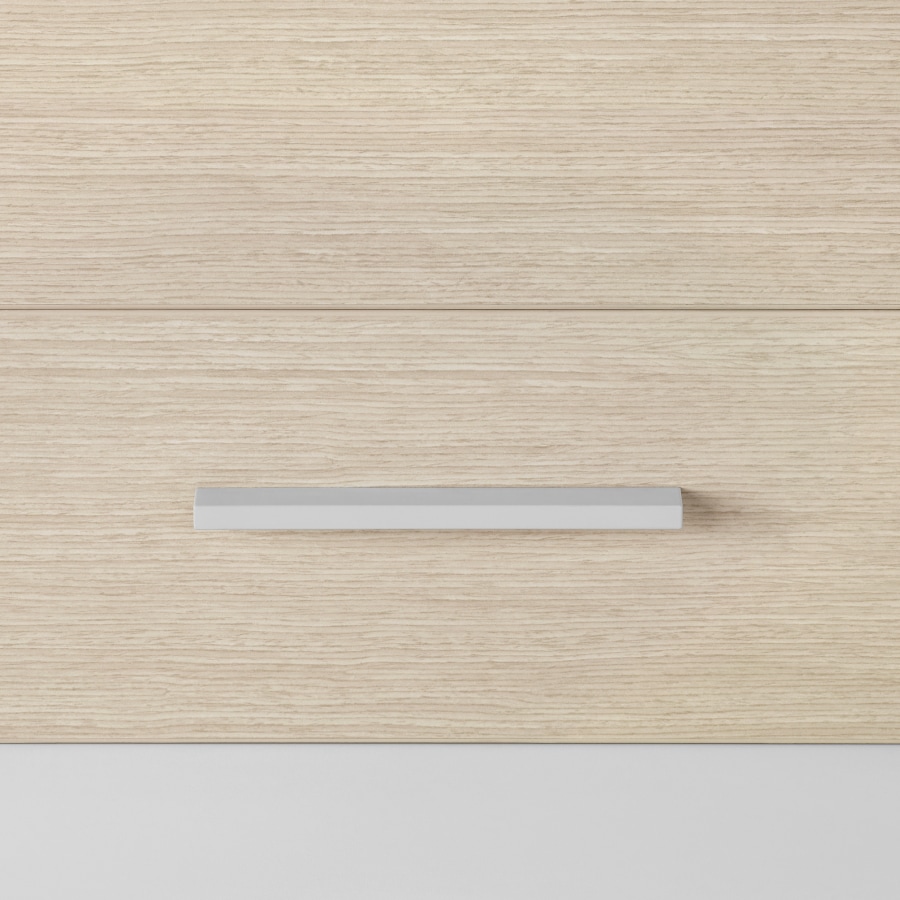A close-up view of a Mora Casework storage drawer in an ash wood finish with a bar pull in a light gray finish.