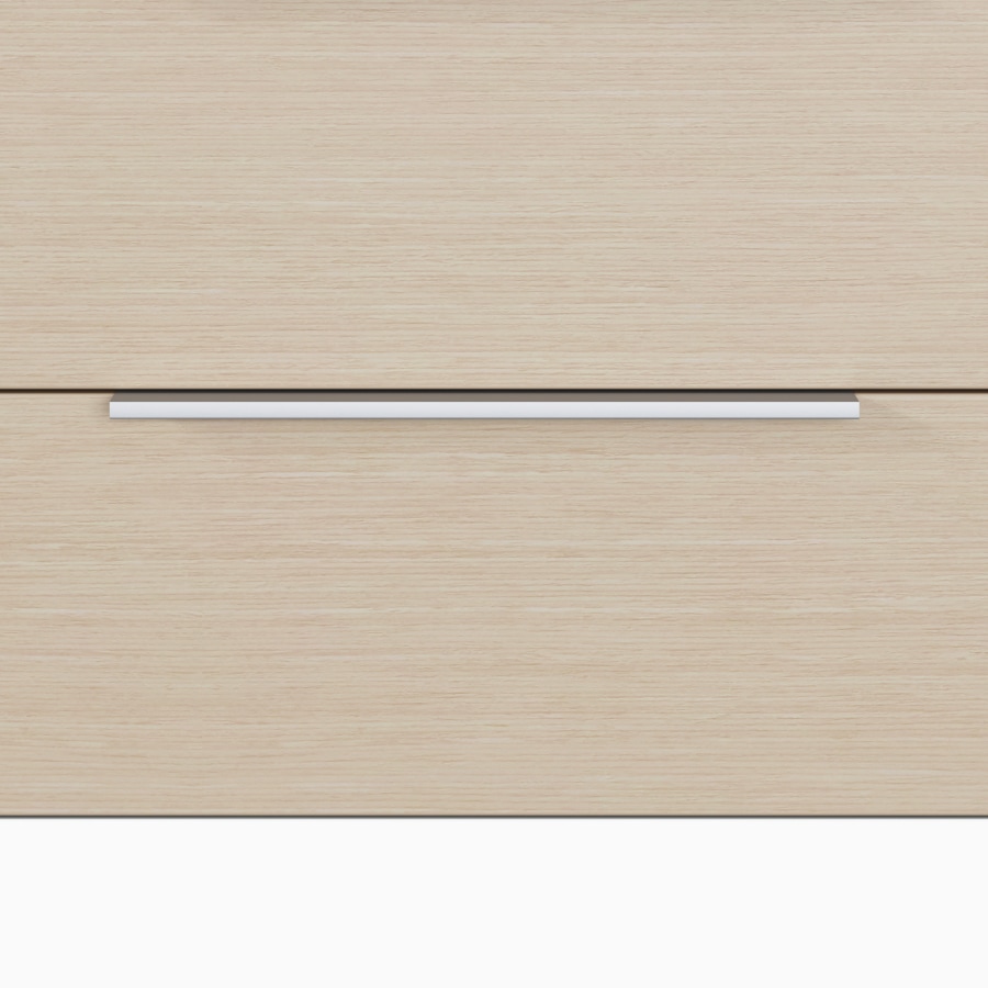 A close-up view of the Mora Casework tab pull in a silver finish on drawers in an ash wood finish.