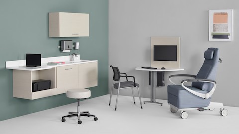 An exam room setting with Mora System casework on the wall in a light wood finish and a Mora peninsula on the side wall located between an Ava patient recliner and a Verus side chair.