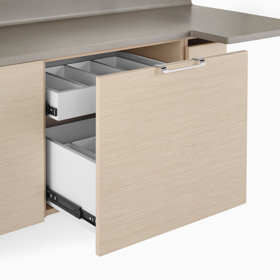 A close-up view of a Mora System casework supply drawer with storage containers inside and a taupe solid surface top.