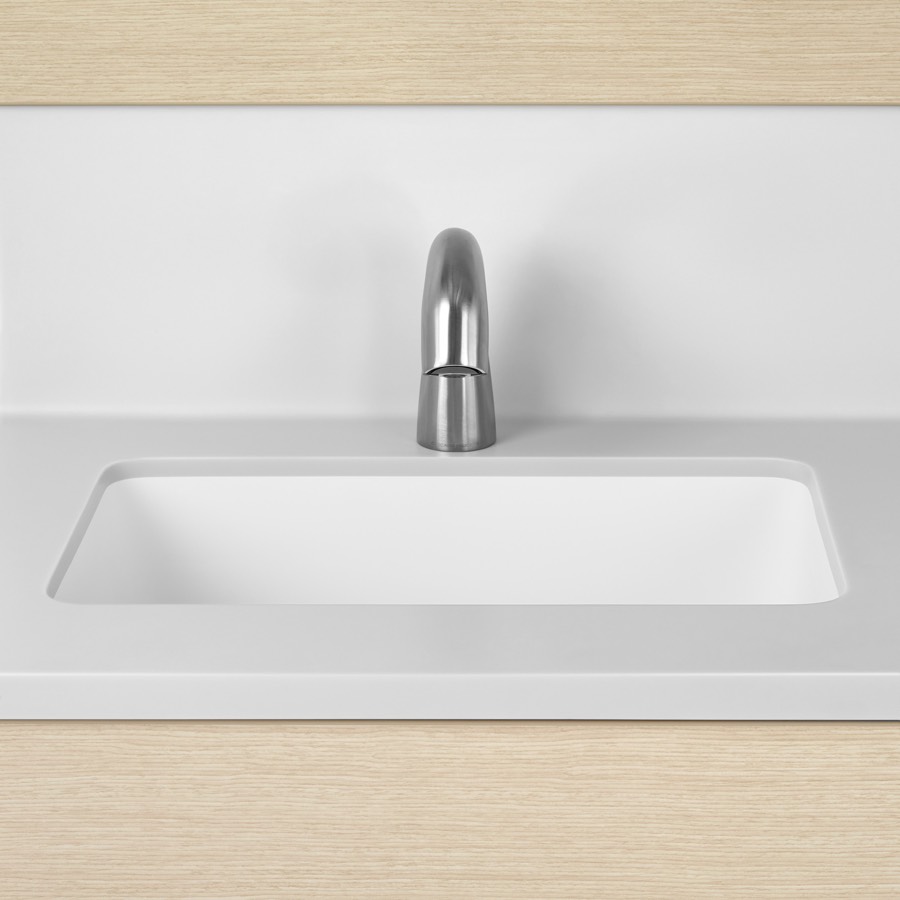 A close-up view of a Mora Systems casework integrated sink and backsplash in white solid surface.