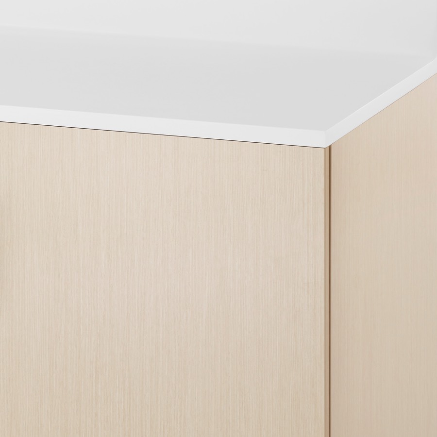 A close-up view of a Mora System casework cabinet in a light wood finish and white Corian surface.