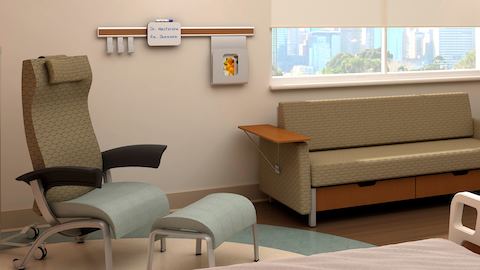 A patient room featuring a Nala Patient Chair and complementary sofa, both with olive green patterned upholstery.
