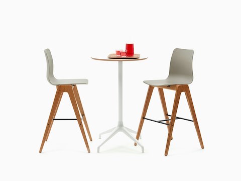 Ali吧台桌，配有白色4星底座和圆形橡木胶合板桌面，搭配两张吧台高度的Polly凳子。