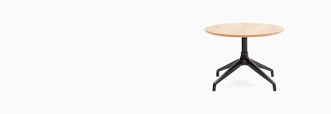 Una mesa de café Ali, con base de estrella de 4 puntas en negro y superficie de chapa de madera circular en roble.