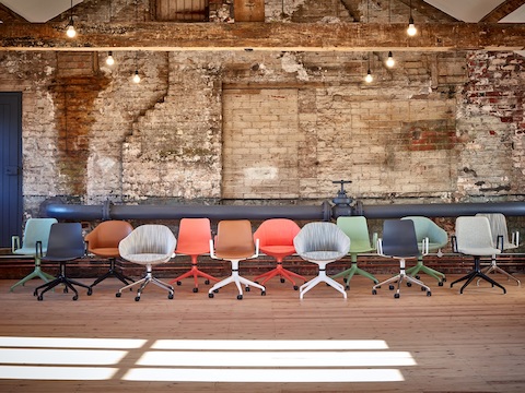 13 NaughtOne Always, Viv and Polly Chairs of various colours and finishes, all with 4- or 5-star bases, arranged in front of an exposed brick wall.