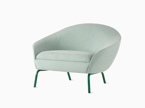 Vista en ángulo frontal de un sillón lounge Ever tapizado en verde pálido con patas de acero en verde oscuro.