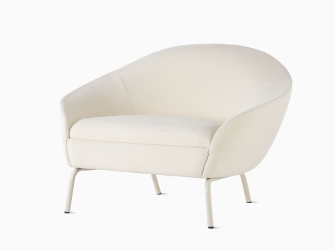 Schrägansicht eines Ever Lounge-Sessels mit Textilbezug in Creme und Stahlbeinen in Perlweiß.