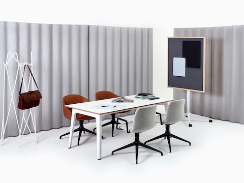Un appendiabiti Shard bianco con una valigetta in una stanza con un tavolo riunione Fold bianco e quattro sedute Polly Wood bianco avorio.