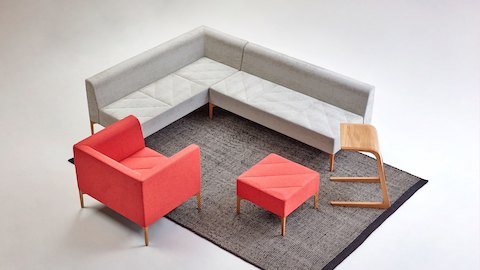 Two grey NaughtOne Hatch Modular Seating pieces are connected in a seating arrangement with a red Hatch Chair and a Hatch Bench. 