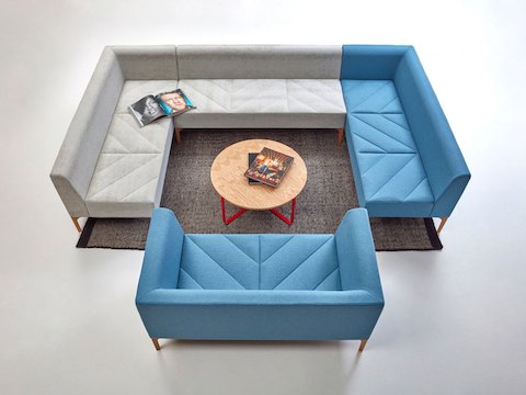 A light blue Hatch Sofa in front of a large couch made of Hatch Modular Seating - two pieces in light blue and one in gray. 