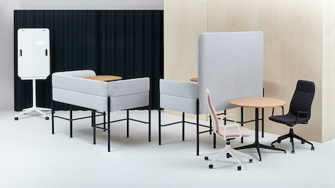 Two-seat, bar-height Hue seating, upholstered in gray fabric with black legs in a collaborative setting. One booth with screen and one without.