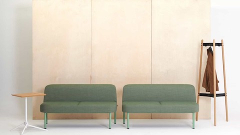 Two green Hue Sofas accompanied by a Knot Side Table and a Hudson Coat Stand.