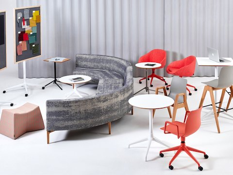 Een oranje NaughtOne Polly-stoel met een 5-ster onderstel in een kamer met uiteenlopende NaughtOne producten: Symbol, Pinch, Polly Wood, Ali en Knot.
