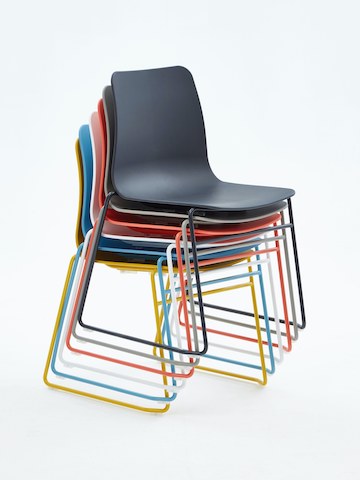 A yellow, blue, white, orange,grey and black Polly Side Chair stacked on top of one another, viewed at an angle.