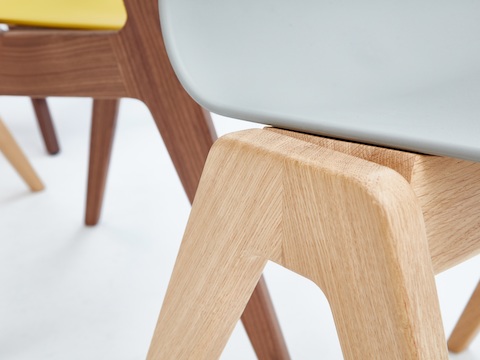 A close-up view of the oak base on a gray naughtone Polly Wood Chair.